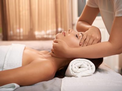 Young woman having calming massage on her face while relaxing in luxurious spa salon